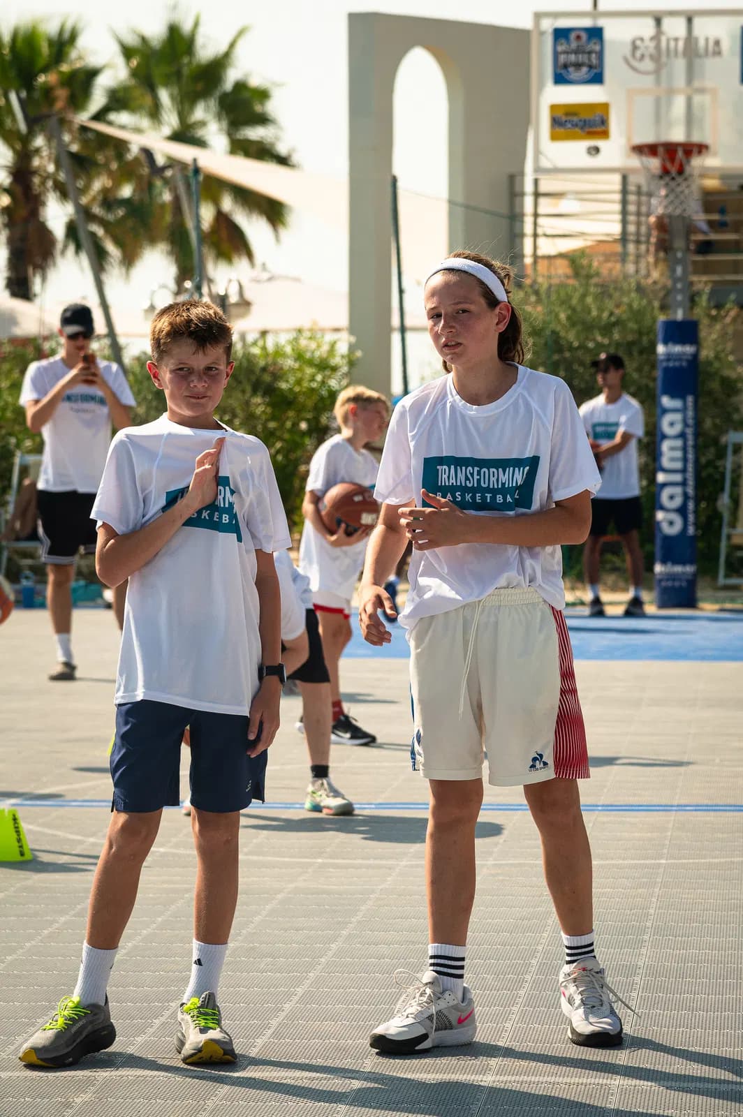 Young players listening on an outdoor court during a Transforming camp session