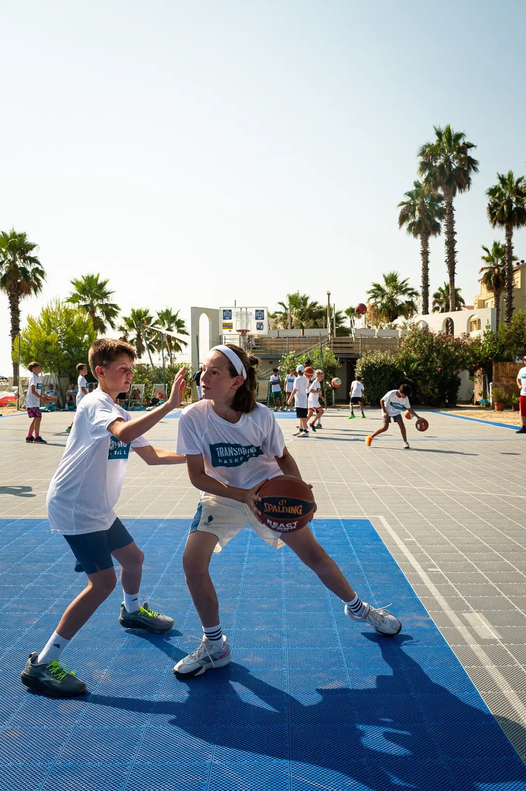 Two young players contesting a live one-on-one read during a small-sided game on an outdoor camp court