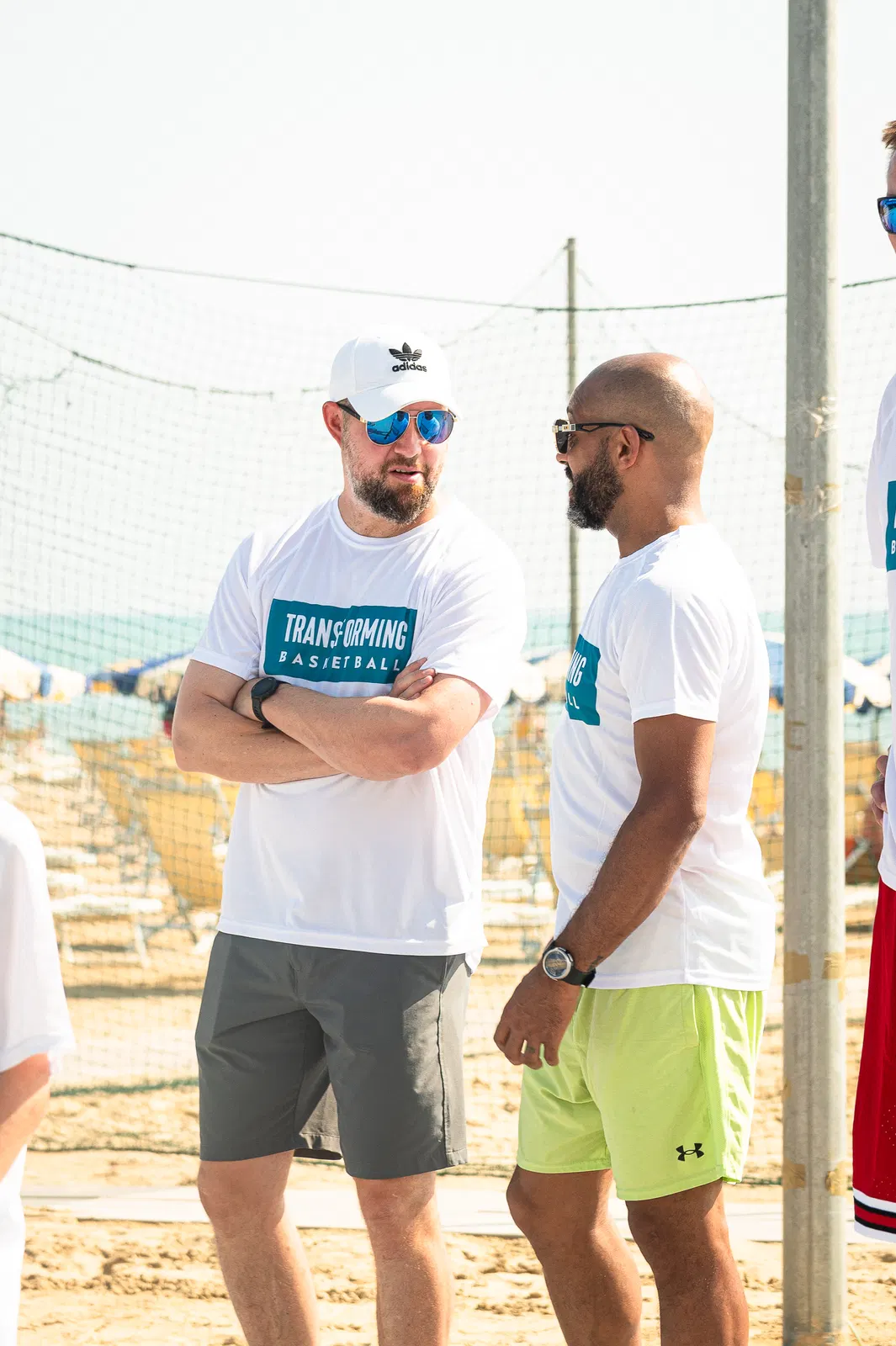 Two coaches in Transforming Basketball shirts talking between sessions at an outdoor camp