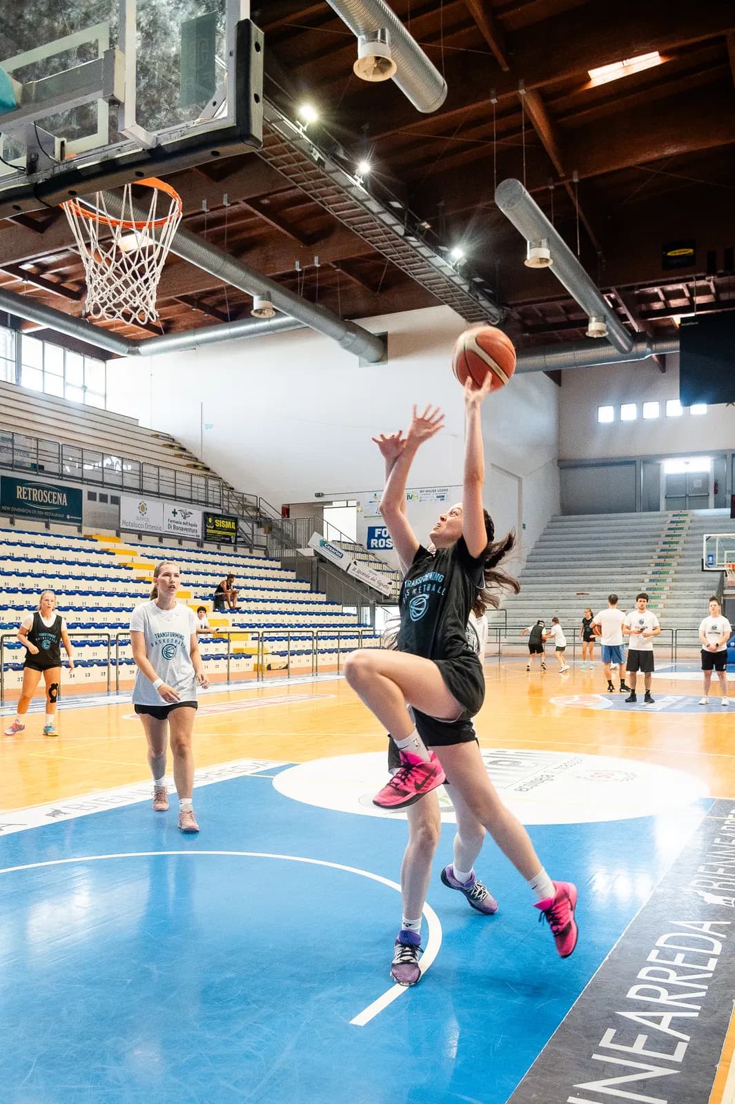 A player finishes near the rim with a defender behind her at Roseto camp