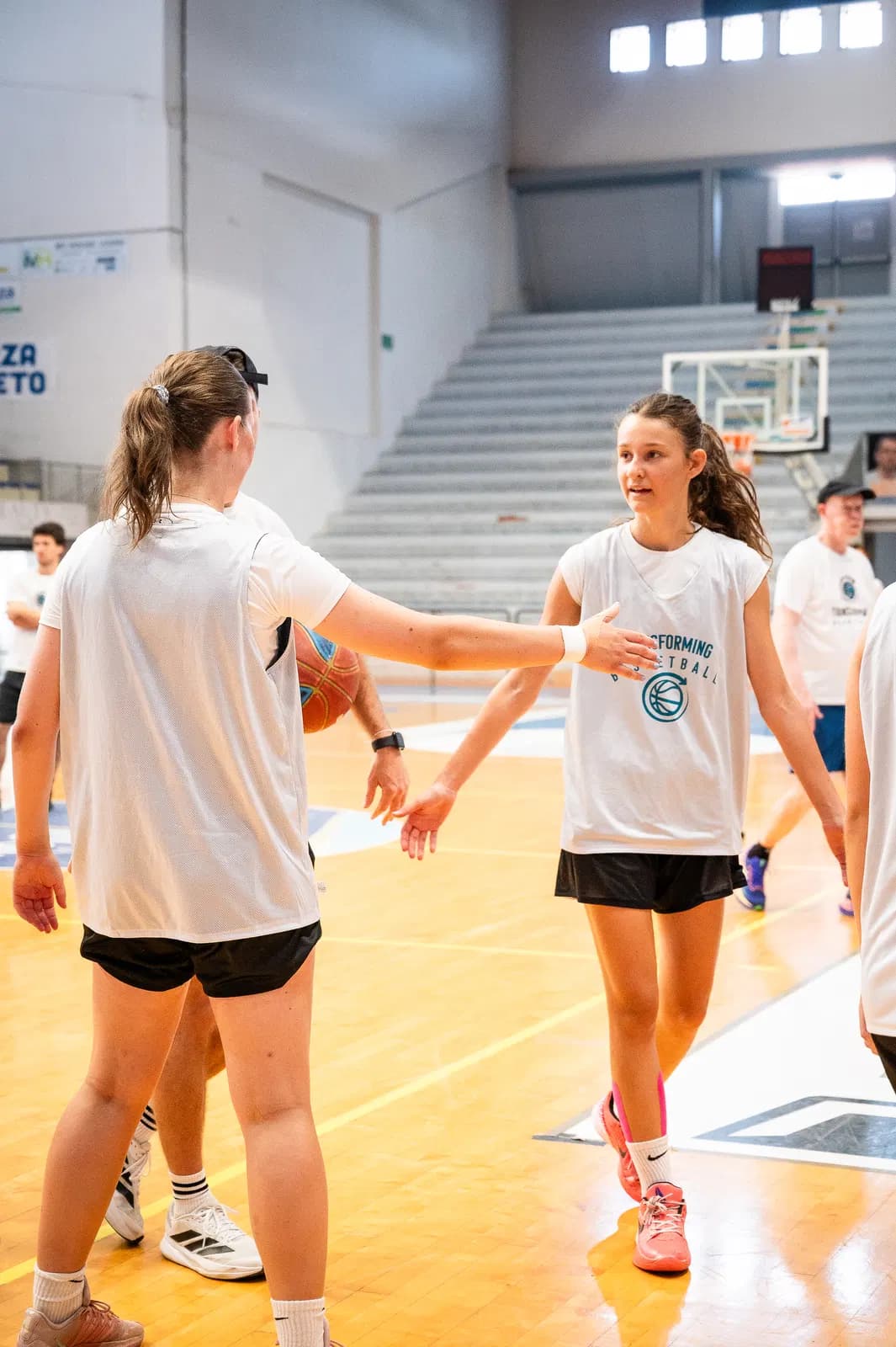 Players lined up on court while a coach observes an evaluation session