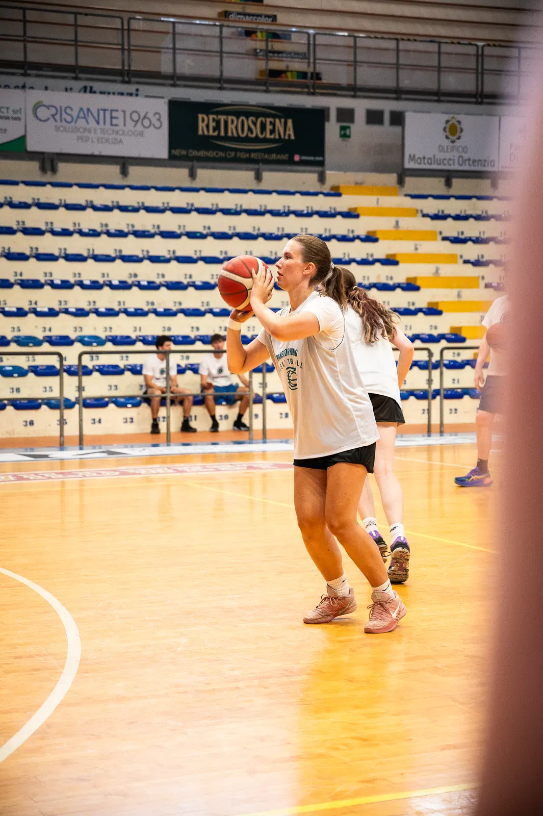 A player in a Transforming Basketball shirt catching the ball and loading to shoot during a camp session