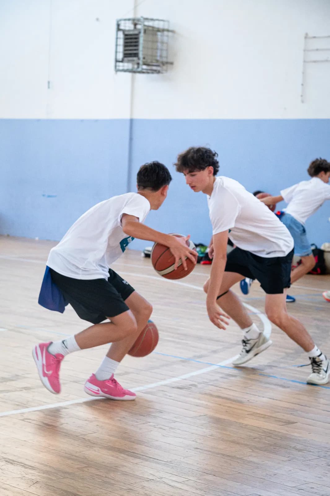 A young player driving with the ball against a defender at a Transforming Basketball camp session in Roseto