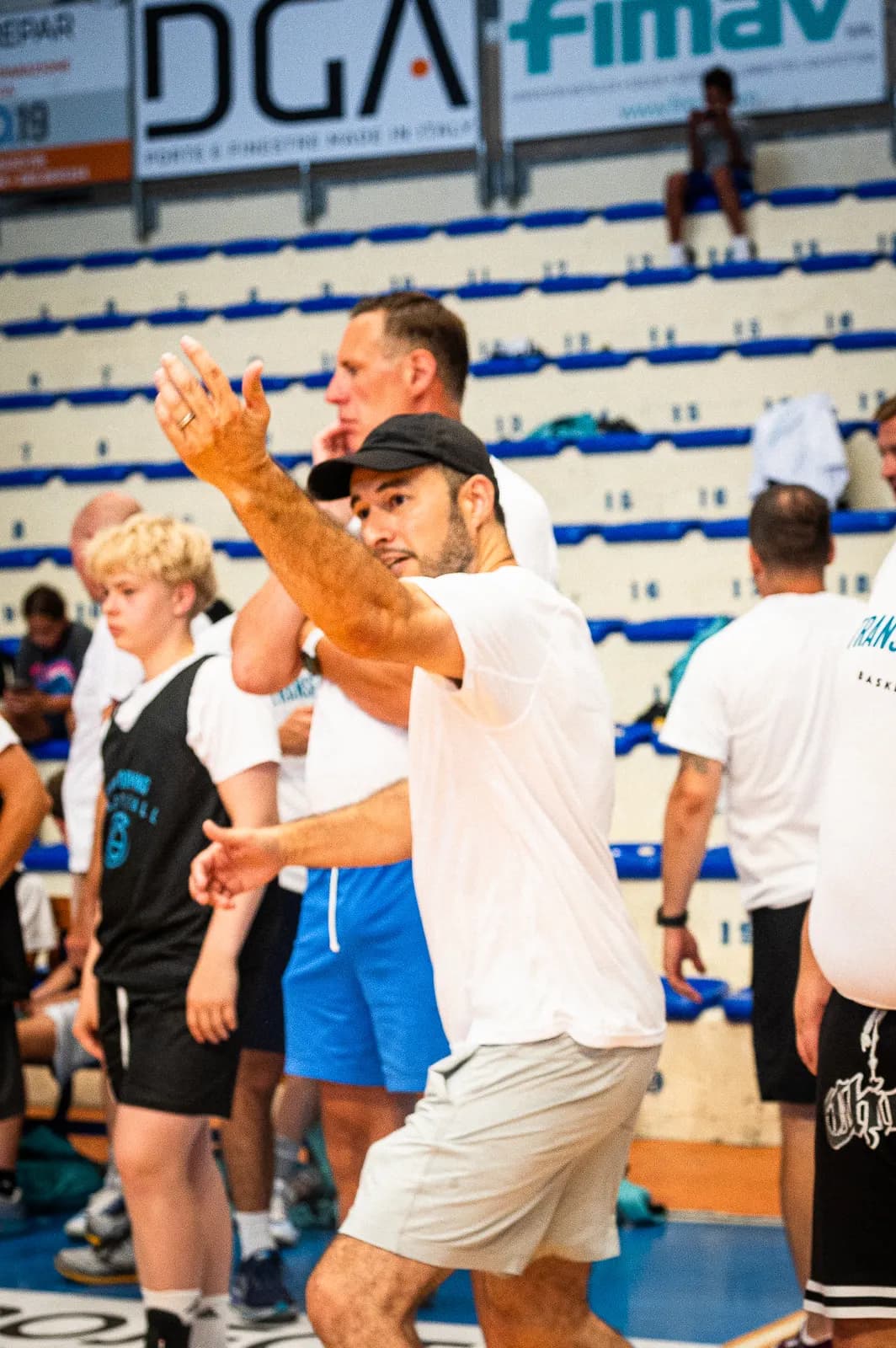 A Transforming Basketball coach gesturing as he gives instructions to young players at the Roseto camp