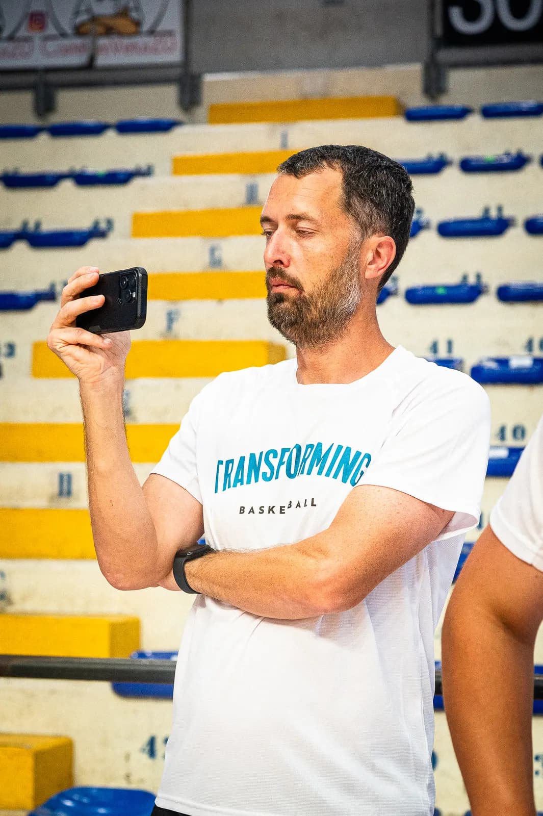 A coach filming practice on a phone to review later