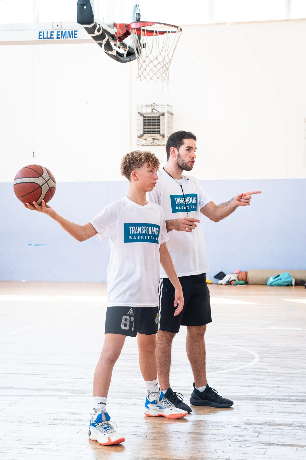 A coach pointing out a passing option to a player holding the ball at the 2026 Transforming Basketball camp in Roseto