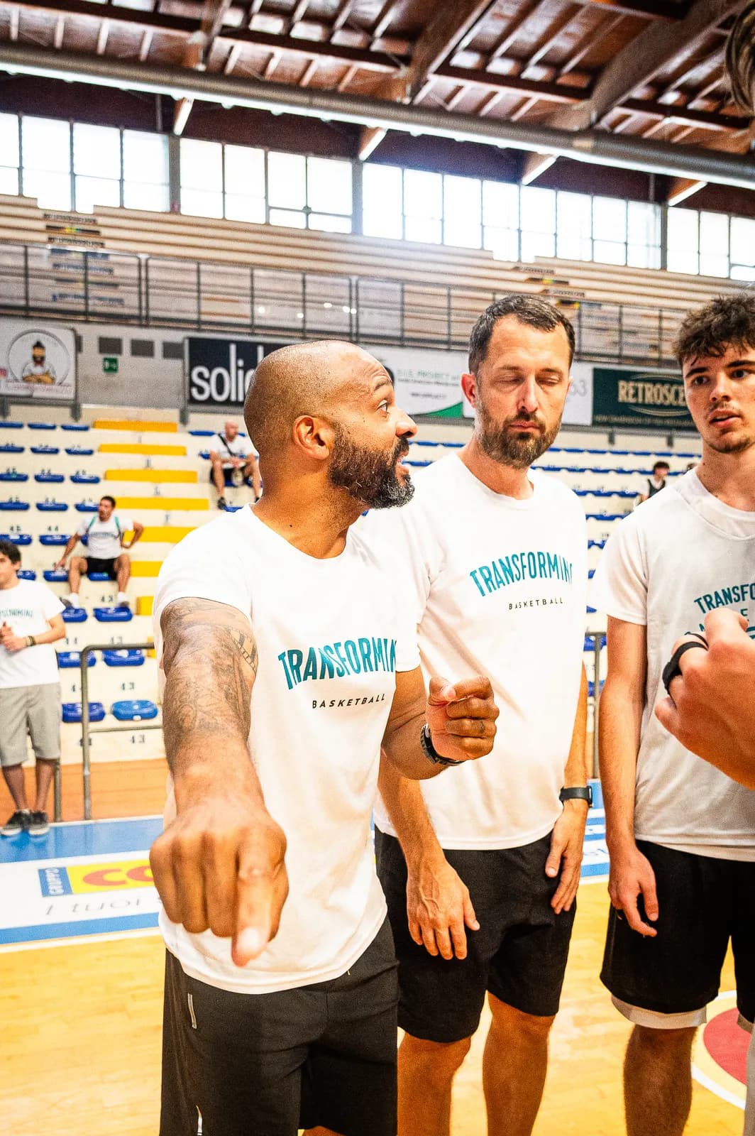 Coaches in Transforming Basketball shirts discussing a session on court