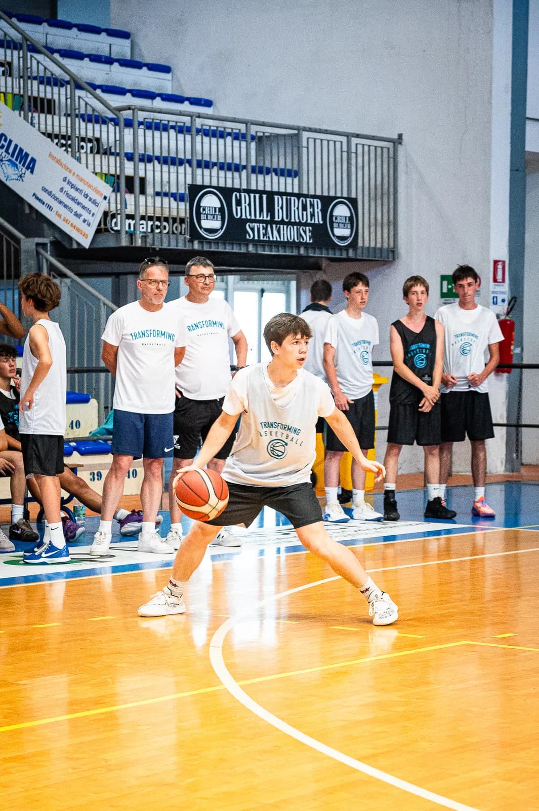 Coaches watching a player work with the ball during a Transforming Basketball camp session in Roseto
