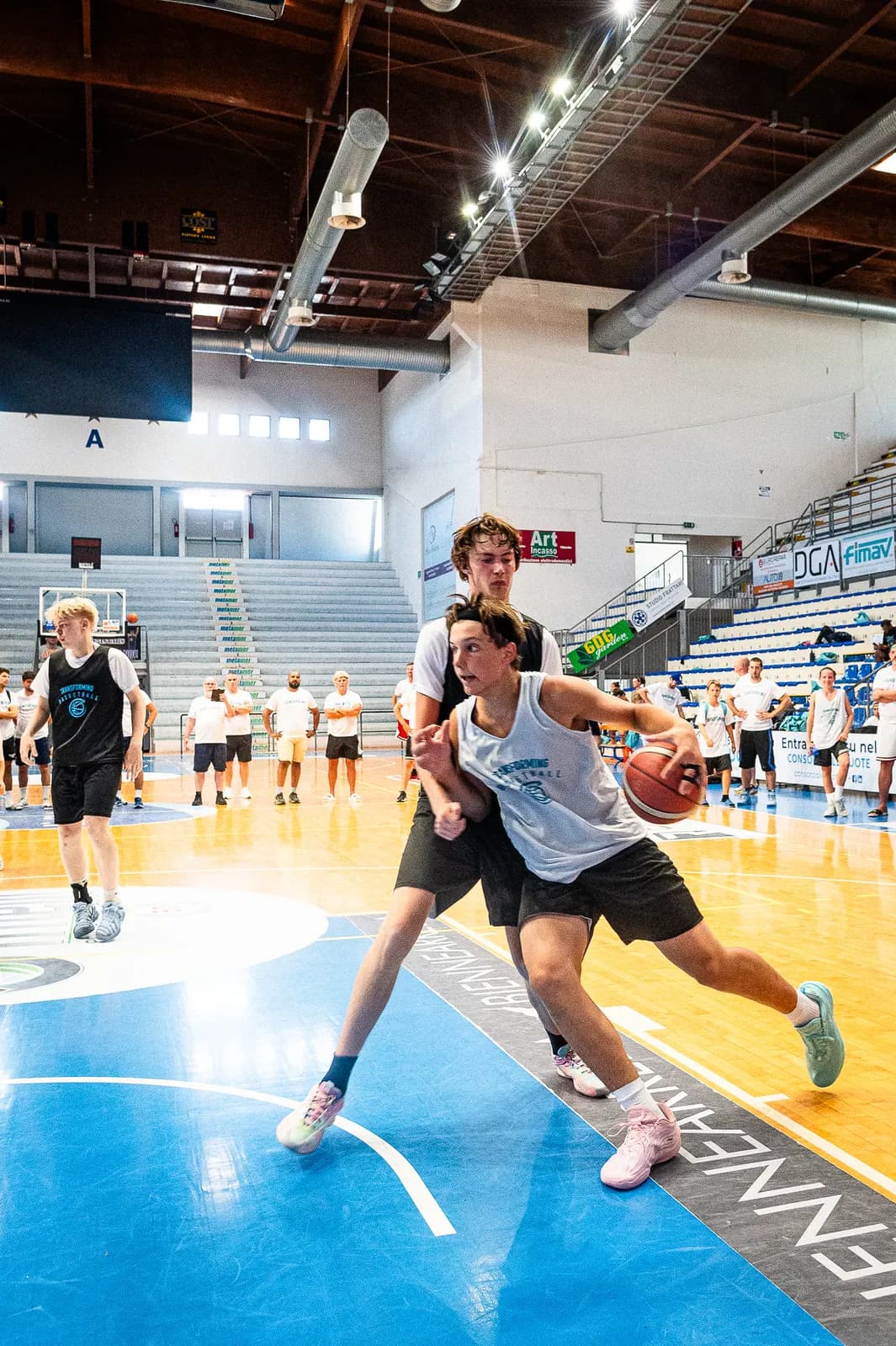 A player driving through contact from a defender at the 2026 Transforming Basketball camp in Roseto