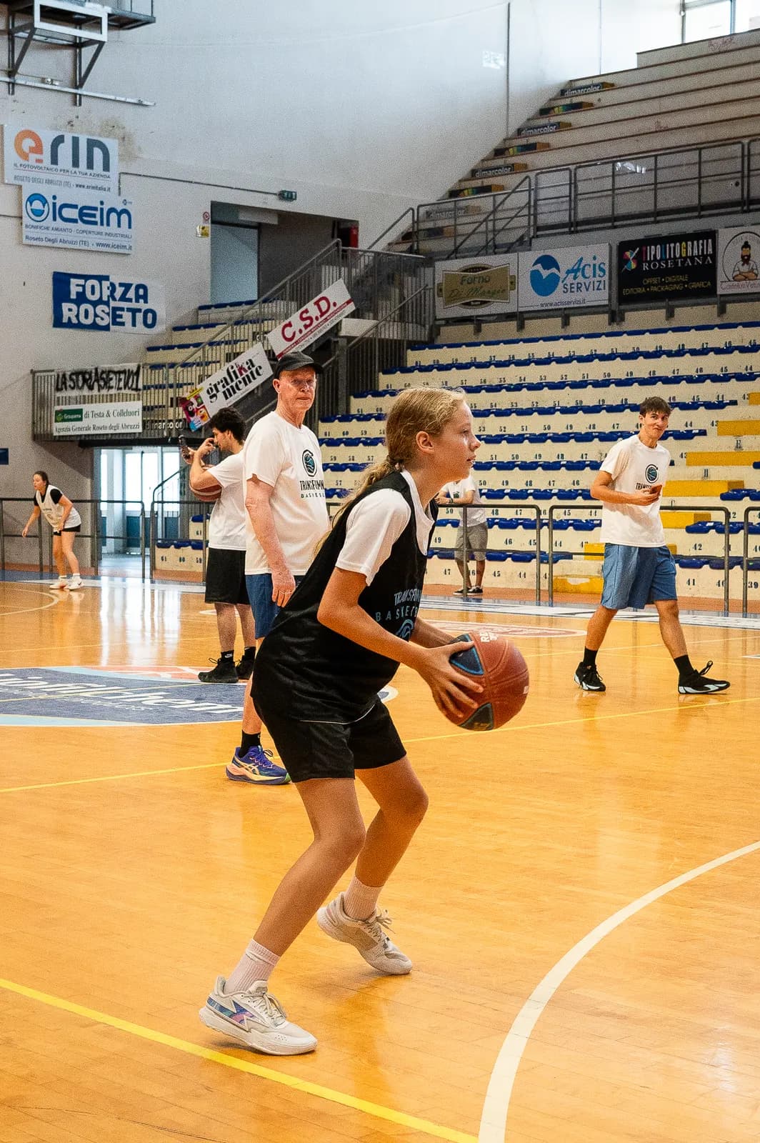 A ball handler pushing the ball up the court in an indoor arena at the 2026 Transforming Basketball camp in Roseto