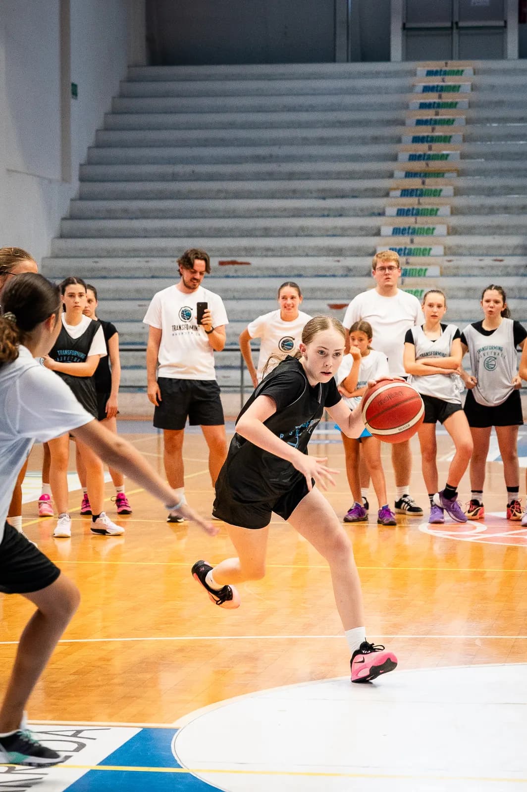 A young player dribbling past a defender during a live game at the 2026 Transforming Basketball camp in Roseto