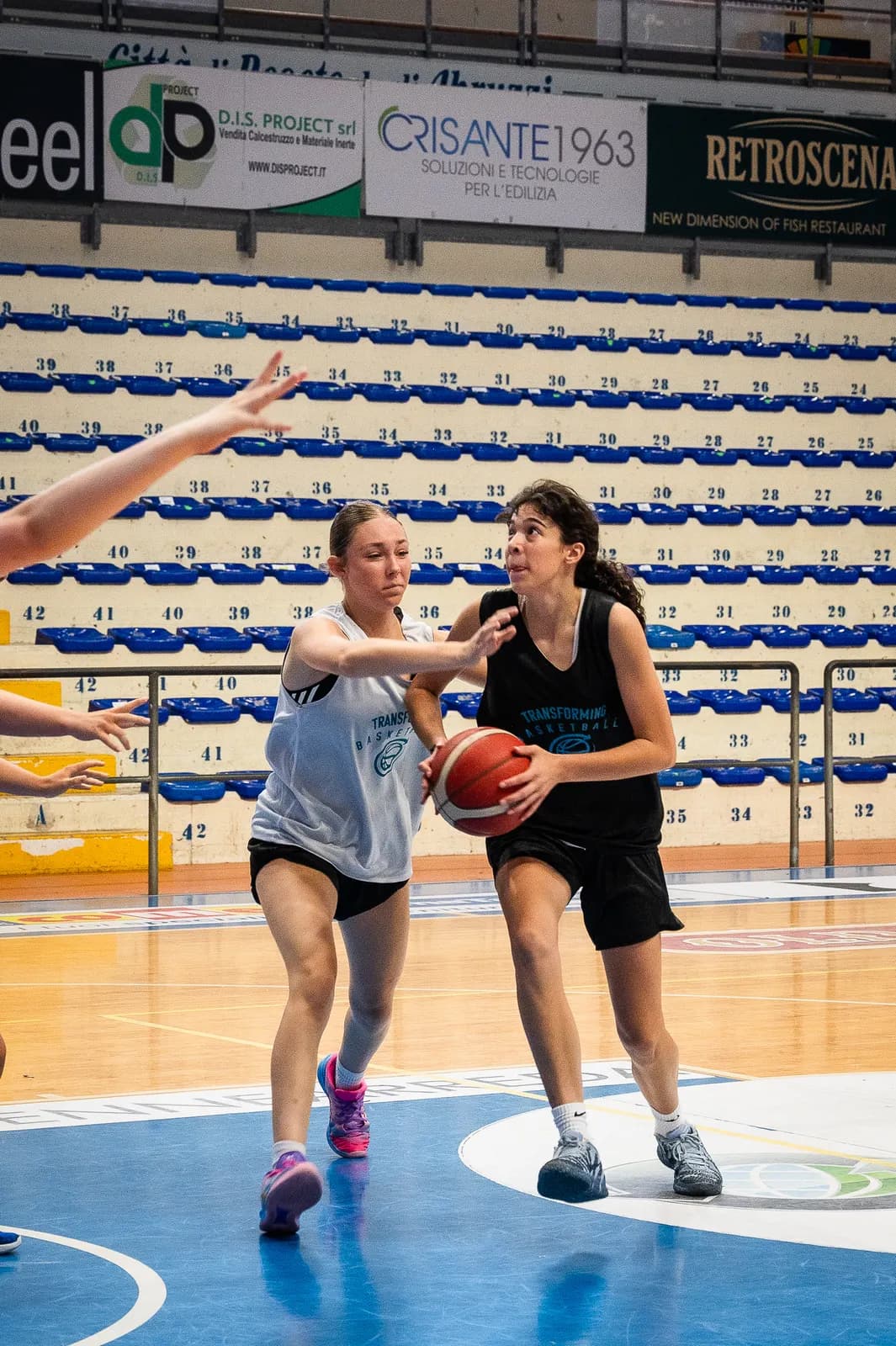 A defender reaching to pressure a ball handler during a live game at the 2026 Transforming Basketball camp in Roseto