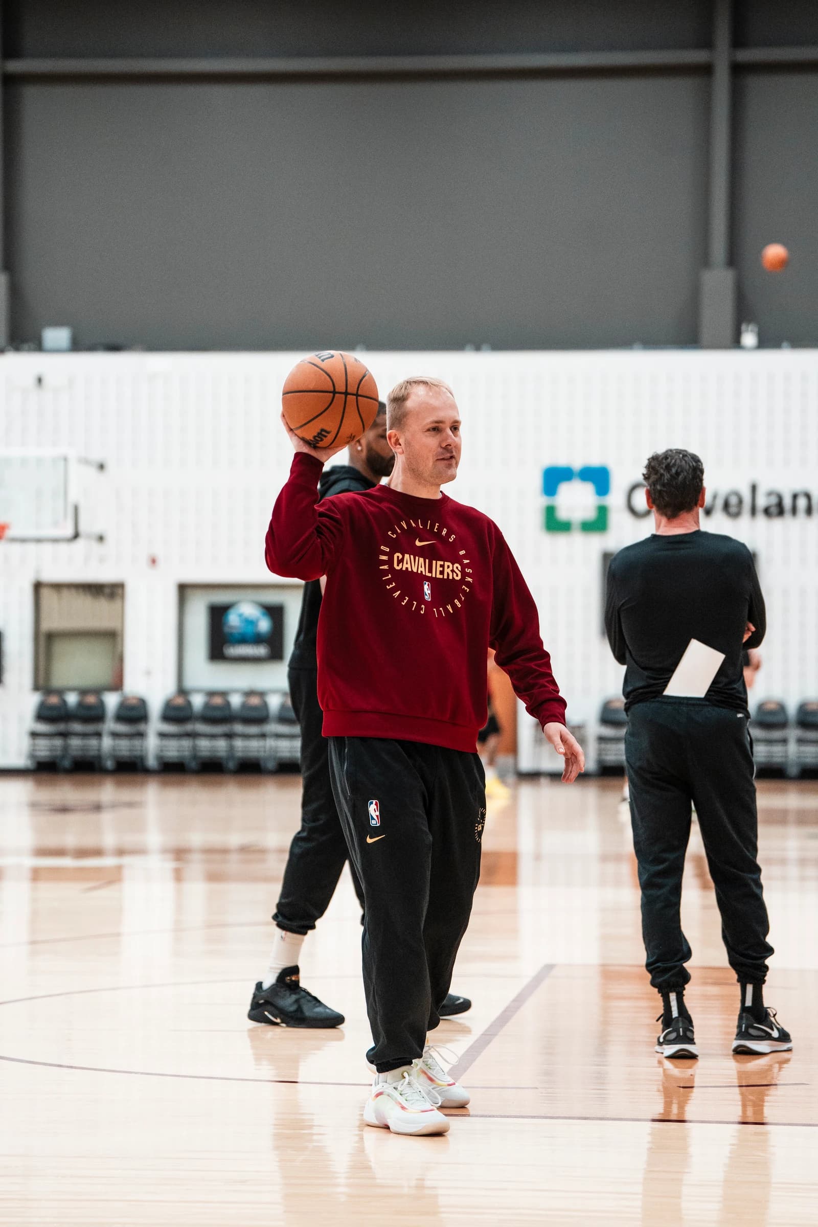 Alex Sarama holding a basketball on court in a burgundy Cleveland Cavaliers top.